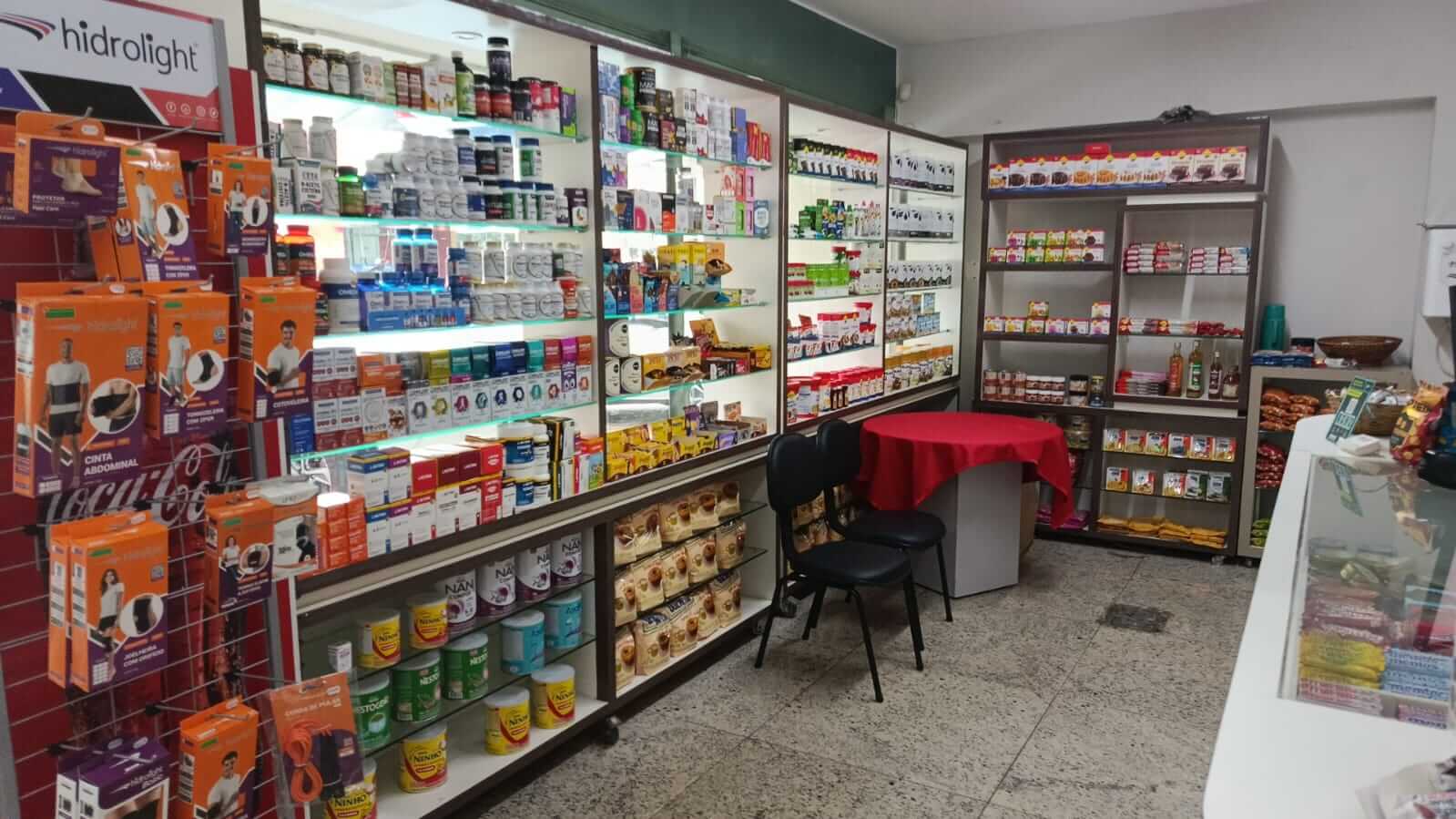 Prateleiras da Farma Diet organizadas com latas de fórmulas infantis Ninho, NAN e Nestogeno, além de suplementos alimentares e espaço de atendimento ao cliente